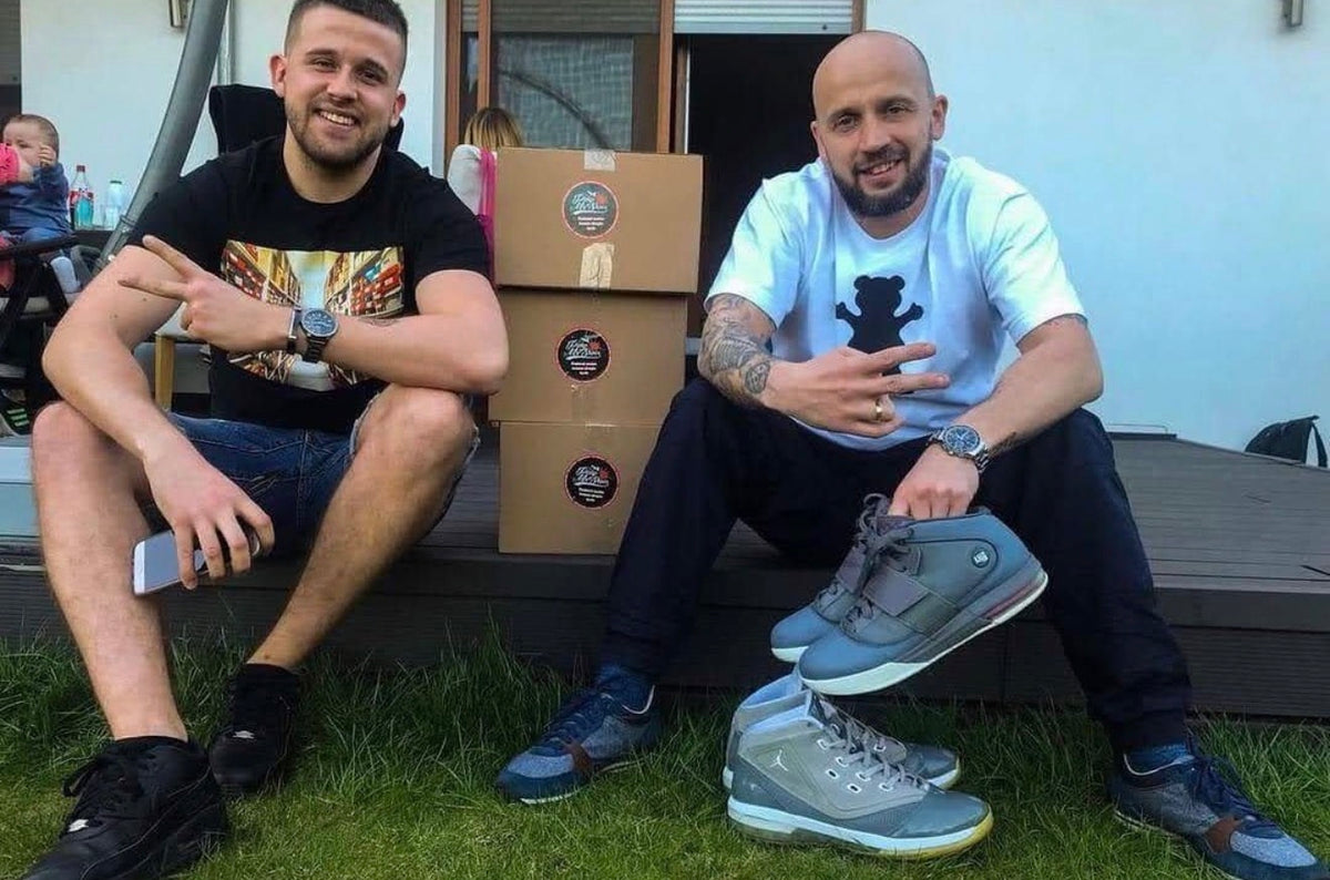 Mati i Peja siedzą obok siebie, pokazując buty przygotowane przez PMS