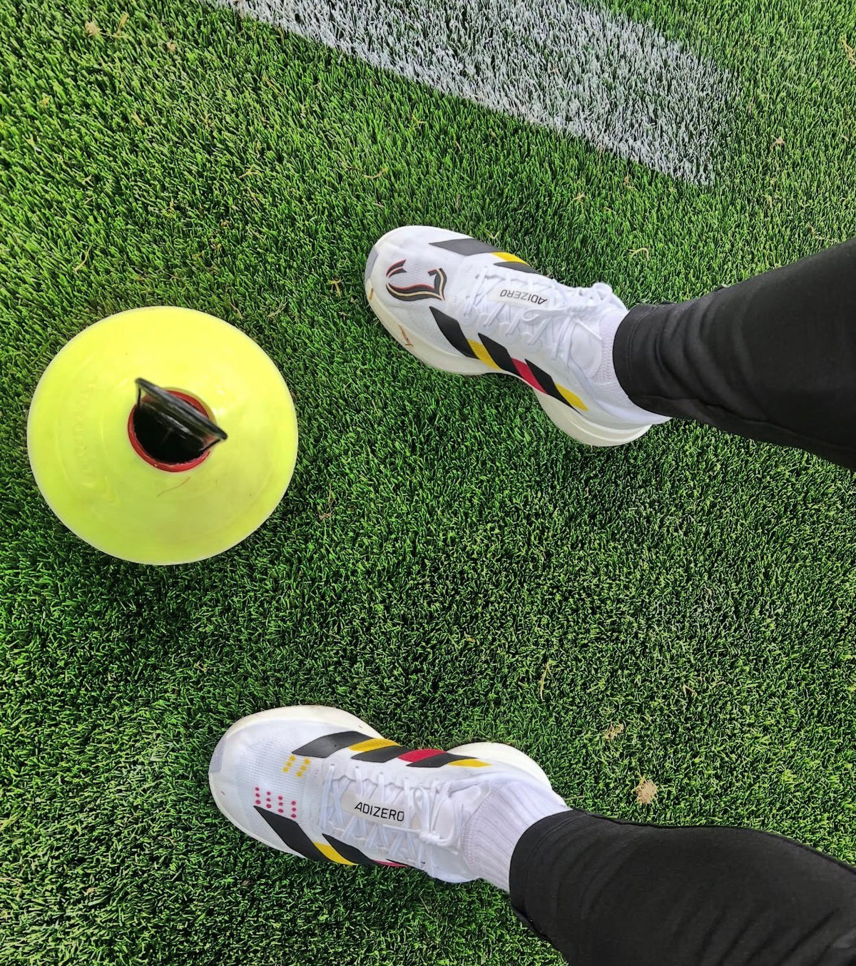 Adidas adizero z herbem i żółto-czerwonymi detalami Jagiellonii Białystok na murawie stadionu